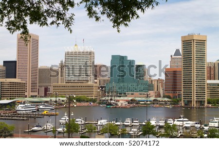 Baltimore city inner harbor showing the city skyline, ship, and pleasure craft docks and boardwalk.