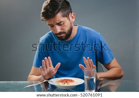 Portrait of man with no appetite in front of the meal. Concept of loss of appetite Royalty-Free Stock Photo #520761091