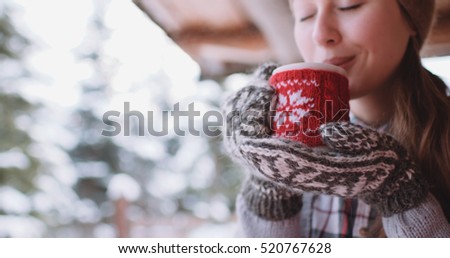 Woman Drinks Hot Tea or Coffee From a Cozy Cup on Snowy Winter Morning Outdoors. Beautiful Girl Enjoying Winter in a Garden with a Mug of Warm Drink. Christmas Holidays