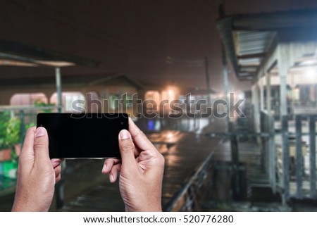 A man holding smartphone at water village.