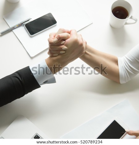 Businessman and businesswoman gripping each others hand, competing in arm wrestling, trying to pin the others arm on office desk. Close up of arms. Rivalry, competitive market. Business concept photo