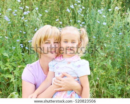 Mother and child are hugging and having fun outdoor in nature on the green grass.