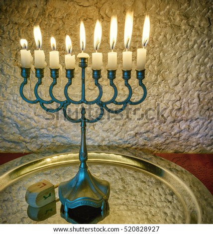 Jewish holiday Hanukkah celebration with vintage menorah and wooden dreidel - traditional symbols of the holiday. Selective focus. Image toned for inspiration of vintage style