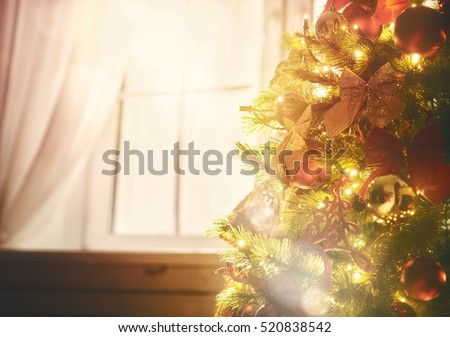 Merry Christmas and happy holidays! Christmas tree with toys baubles close-up on window background.
