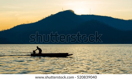 silhouette of a man are boating in the dam on the morning.