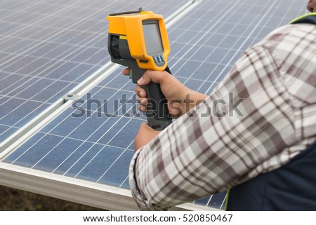 engineer or electrician working on  maintenance equipment at industry solar power;  engineer using thermal imager to check temperature heat of solar panel 