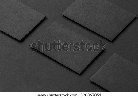 Mockup of four black business cards arranged in rows at black paper background.