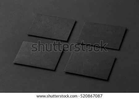 Mockup of four black business cards arranged in rows at black paper background.
