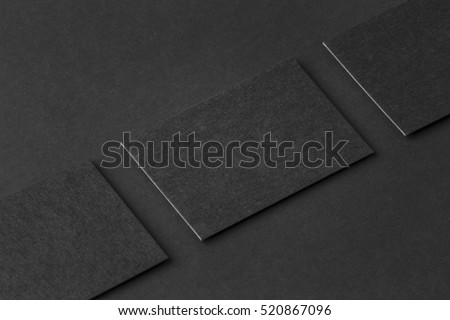 Mockup of three horizontal business cards at black textured paper background.