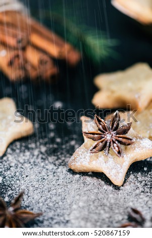 Star shaped cookies with cinnamon and anise on the table being scattered with sugar powder