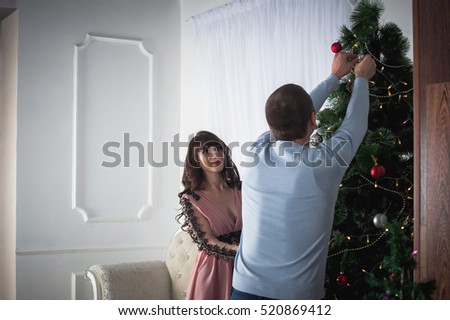 Beautiful couple celebrating Christmas. Lovers celebrate the New Year at home and decorate the Christmas tree.