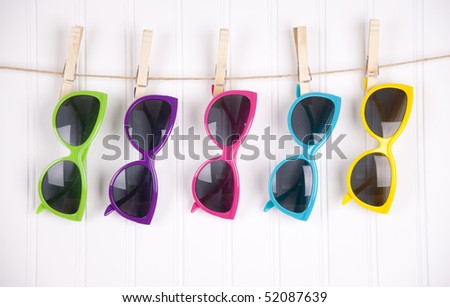 Hip summer sunglasses hanging on a white clothesline. Royalty-Free Stock Photo #52087639