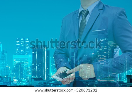double exposure of business man using telephone or tablet on night modern city building background