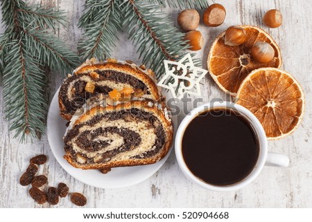 Poppy seeds cake on plate, cup of coffee and spruce branches, dessert for Christmas, rolled up traditional polish poppy pie