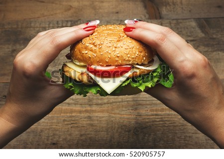 Eating hamburger. Delicious hamburger in the hands. Fastfood meal. Vintage toned Royalty-Free Stock Photo #520905757