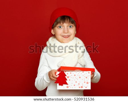 girl child portrait with gift box on red, winter holiday concept