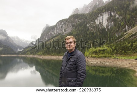 A traveler on the background of an alpine lake Gosausee in cloudy weather, Austria 