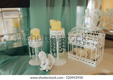 Stylish candlesticks with candles and a statue of an angel on the location of the wedding ceremony.
