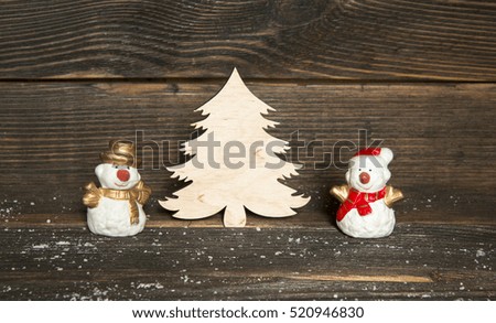 toy snowmen and wooden Christmas tree on a dark wooden background. The concept of Christmas and New Year