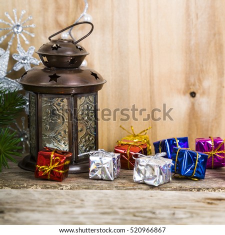 Christmas decorations on the wooden background. Silver snowflake, lantern, decorative branches and boxes with gifts.