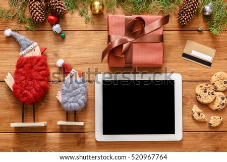 Christmas online shopping background. Tablet screen with copy space top view on wood, credit card, xmas toys ans presents. Electronic devices, internet commerce on winter holidays concept