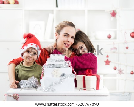 Two kids and their mother are opening Christmas presents in their living room.