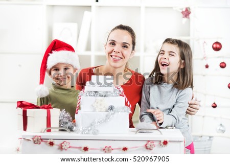 Two kids and their mother are opening Christmas presents in their living room.