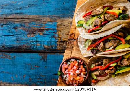 Mexican pork tacos with vegetables and salsa. Tacos al pastor on wooden blue rustic background. Top view. Copy space