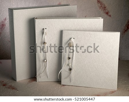 Three ivory white photo albums on textured background