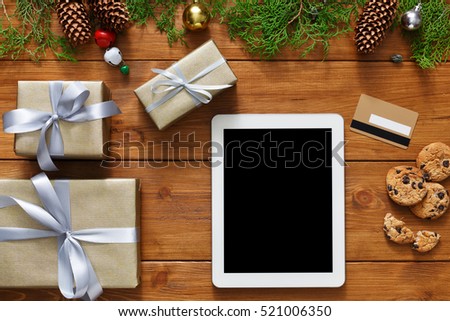 Christmas online shopping background. Tablet screen with copy space top view on wood, credit card and present boxes. Electronic devices, internet commerce on winter holidays concept