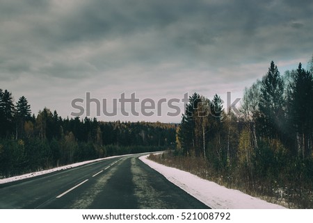 empty road in the countryside with trees in late autumn with snow. vintage film effect