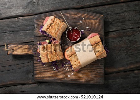 Sandwich with beef meat on wooden board on dark table, top view