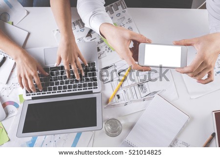 Young man and woman taking picture of messy desktop with smartphone. Mock up, Teamwork concept