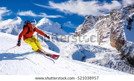 Skier skiing downhill in high mountains against sunshine