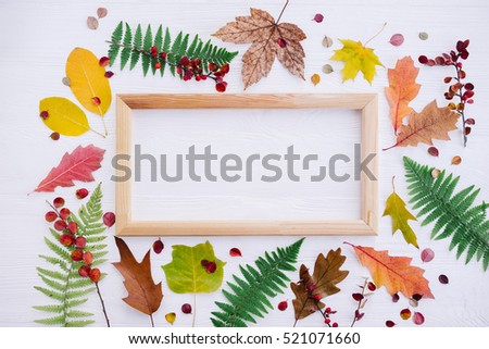 Composition with autumn leaves and picture frame on white wooden background. Flat lay, copy space.