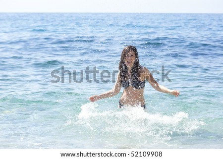 Young playful girl splashing on the beach