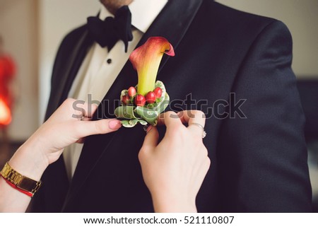 bridesmaid pinning boutonniere with calla and red berries