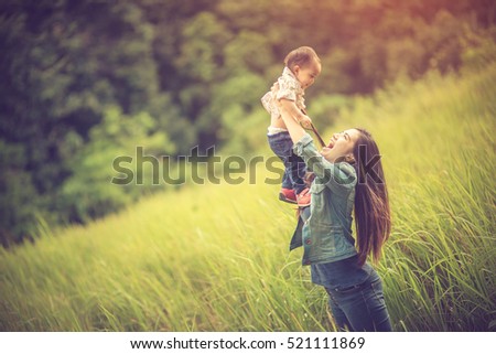 Mother and little daughter playing together in a park.Vintage color
