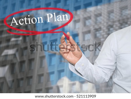 Hand of young businessman write the word Action Plan on skyscrapers background,concept of Apply to promote your business or work presentations.