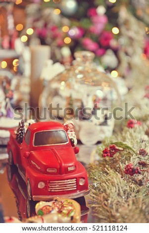 Toned image of Adorable christmas red car toy with santa and presents. Musical miniature decoration on tree bokeh background