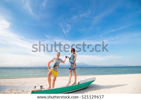 Happy young joyful couple having beach fun laughing together during summer holidays vacation on tropical beach with white sand. Beautiful energetic fresh interracial multi-ethnic couple, man and woman