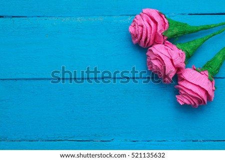 Fresh roses flowers in ray of light on turquoise painted wooden background. Selective focus.