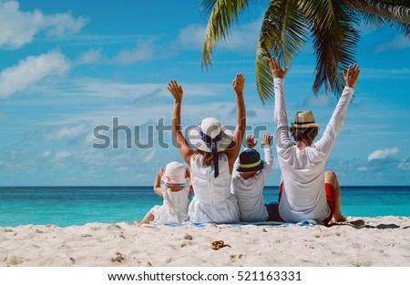 happy family with two kids hands up on the beach Royalty-Free Stock Photo #521163331
