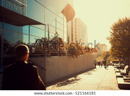 Businessmen near the entry into the business center. Skyscrapers with glass facade. Modern buildings. Concepts of economics, financial, future. Copy space for text. Dynamic composition. Toned