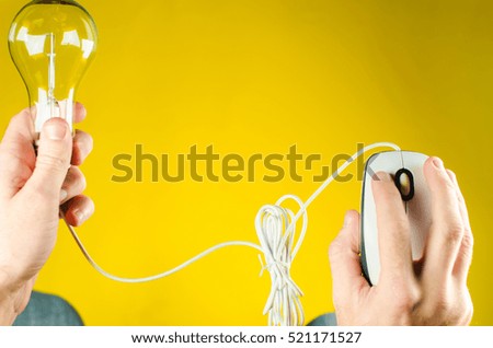 Computer mouse and bulb in hand on a yellow background