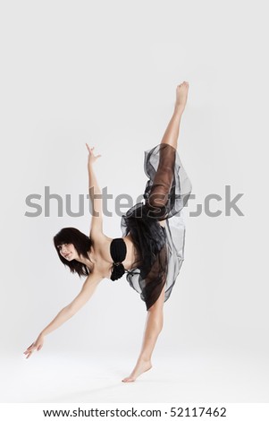 Beautiful female ballerina doing split against white background