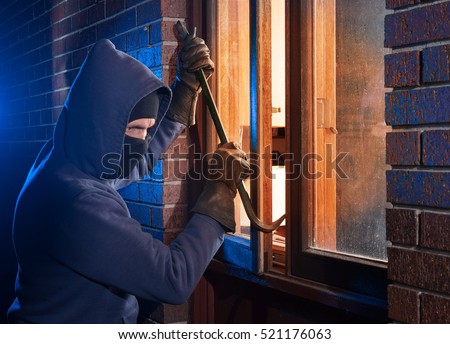 Burglar Using Crowbar To Break Into a House at night with room left and right for type Royalty-Free Stock Photo #521176063