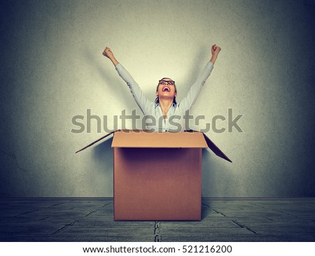 Happy young woman coming out from a small box