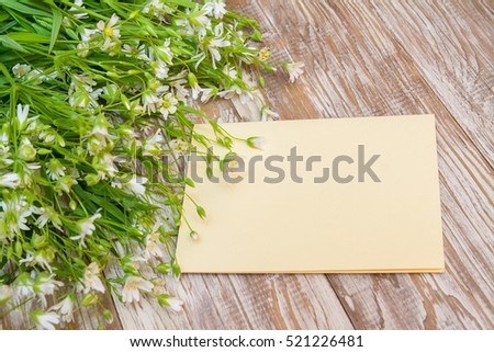bouquet of white small flowers like star. Black greeting card, blank on shaby wooden background.