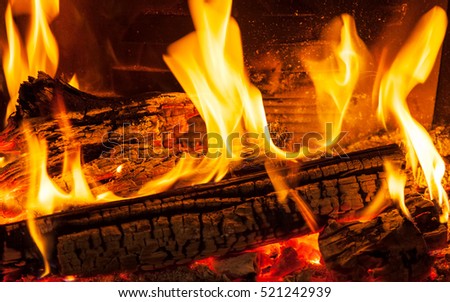 Burning firewood in the fireplace closeup, glowing logs, fire and flames